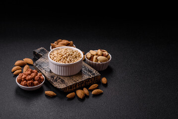 Peeled pine nuts in a bowl on a dark concrete background