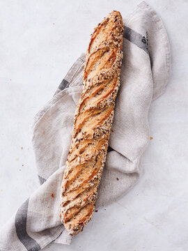 A crusty loaf of artisanal bread lies elegantly wrapped in a soft linen cloth, showcasing its golden brown crust and intricate scoring. The warm atmosphere reflects a sense of comfort and home