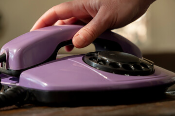 Woman hand picks up telephone receiver of landline phone close-up