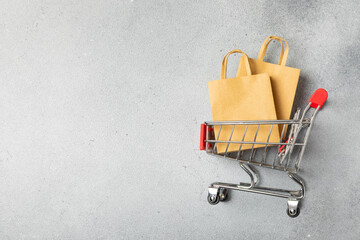 Online shopping concept.Cardboard box and shopping bags in a trolley on a bright colored...