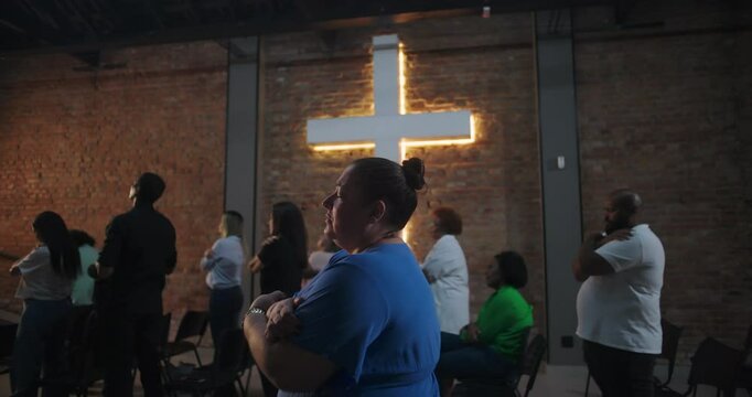 Group of diverse people standing in worship with a cross in the background, deep introspection and self-reflection during spiritual gathering