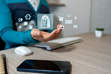 E-commerce and entrepreneurship concepts. A businessman sits in an office and holds a hologram with commerce icons