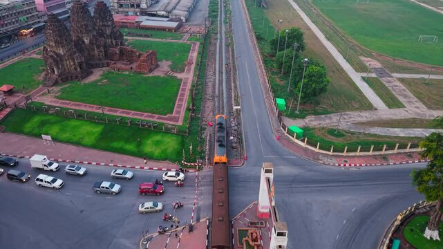 Aerial view of a freight train passing through the city center on the way to Phra Prang Sam Yod temple in Thailand