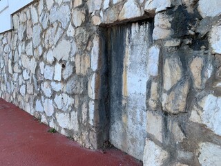 A mysterious sealed doorway or wall recess in a rustic stone facade in Andalusia, Spain. Timeworn...