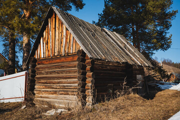 Nestled in the expansive heart of a vast, open field, there stands a quaint and charming, small wooden house characterized by a sturdy roof that adds significantly to its rustic appeal