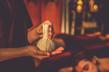Hot herbal ball spa massage body treatment with masseur's hand hold or show herb bag at spa....