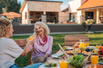 Happy family enjoying garden party with healthy food and orange juice