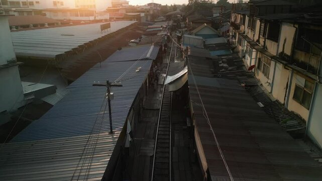 Train passing through Maeklong Railway Market in Thailand, squeezing between market stalls with goods just inches from the tracks
