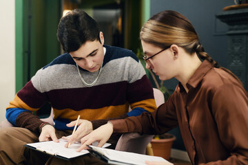 Businesswoman examining cv of young job candidate at their meeting in office