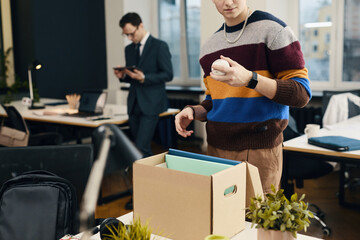 Employee unpacking his things from box on new workplace in office