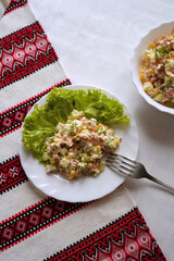 Homemade crab stick salad typical of modern Ukrainian cuisine and other Eastern European cuisines Traditional Ukrainian food on the table with embroidered tablecloth.