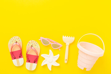 Children's flip flops and beach toys on color background,,top view