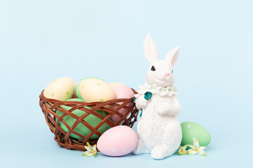 Easter bunny with painted eggs on color background