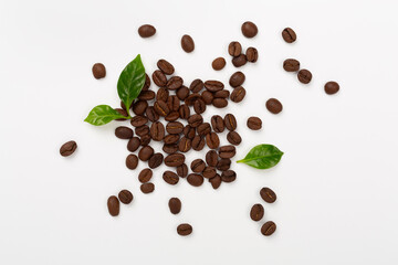 Roasted coffee beans with leaves on white background,top view