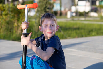 Boy with diabetes riding a scooter, smiling at the camera, glucose sensor visible.