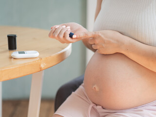 Pregnant woman doing home blood sugar test. Gestational diabetes. 