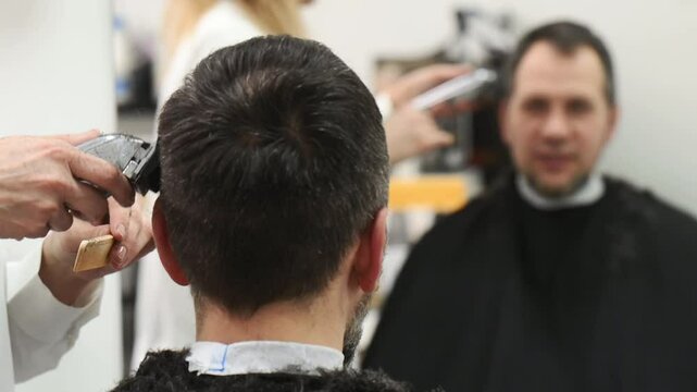 Female barber trims with razor and clipper to male client in beauty salon. Professional barber. Professional hairstylist care 