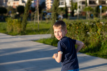 Boy with diabetes riding a scooter, smiling at the camera.