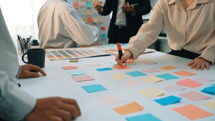 A dynamic scene of a team engaging in a brainstorming session using colorful sticky notes. The...