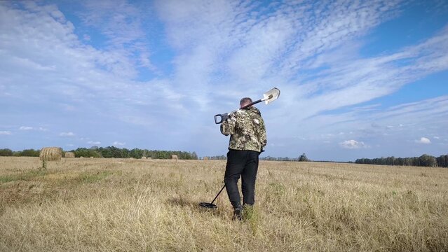 man in a field with a metal detector. treasure hunter searches for valuable metal using a metal detector. Treasure hunt concept.