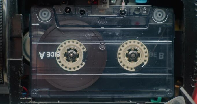 Retro Audio Cassette Tape Playing 80s Mixtapes Sound On Tape Player. Playback of Old Music Using Hi-Fi Vintage Sound System with Nostalgic Atmosphere. Reel-to-Reel Tape Recorder. Macro Close Up.