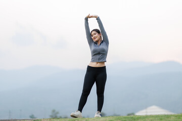A young woman is jogging lightly and stopping to stretch her muscles, warming up her body before starting her full workout.