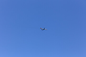 Fototapeta premium A plane is flying in the sky above a clear blue sky