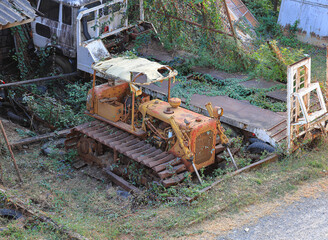 Fototapeta premium Yellow abandoned tractor was discovered in an abandoned warehouse on the outskirts of town.