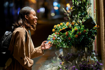 Woman choosing flowers at a street stall by night