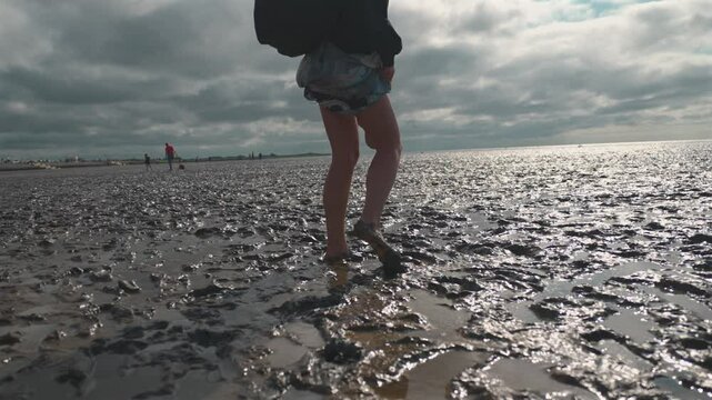 Young Woman Walking Barefoot Along the Wadden Sea Shore in Norddeich at Low Tide