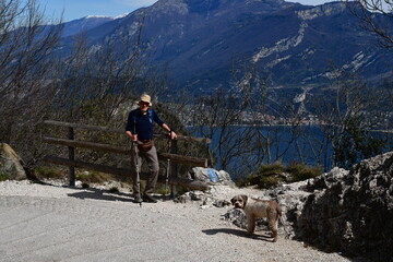 Mann und sein Lagotto Romagnolo Hund wandern oberhalb vom Gardasee