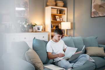 Young man managing bills and finances on laptop at home