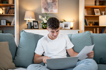 Young man managing finances on laptop at home