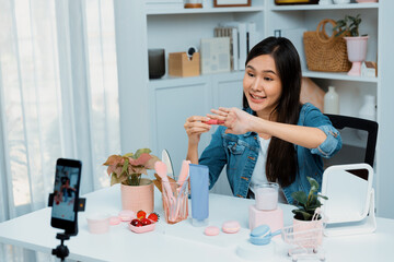 Young beautiful Asian showing cosmetic makeup lipstick matte pastel color testing in bestseller...