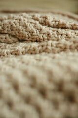 Soft focus on a beige chunky knit fabric in close-up view