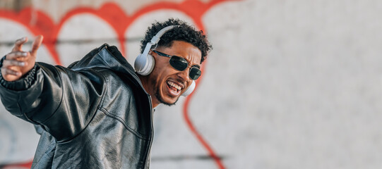 euphoric young man with headphones dancing in the street