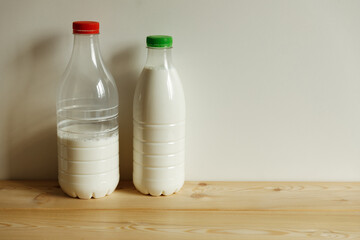 Two transparent plastic milk bottles on the table on a light monochrome background.