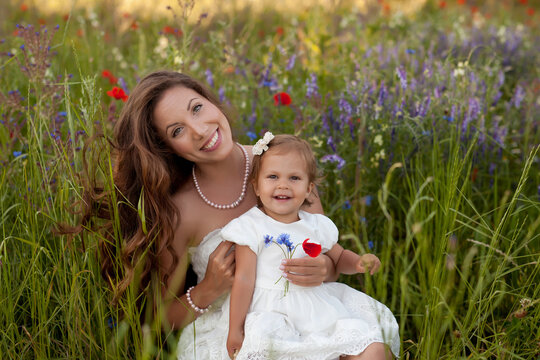Portrait of a smiling mother and daughter sitting a wildflower meadow in summer, Bulgaria