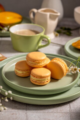 Delicious orange macarons resting on a green plate, ready for breakfast