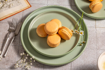 Delicious orange macarons resting on green plates, ready for enjoyment
