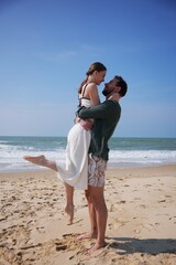 Loving couple embracing on beach during romantic summer holiday by the sea