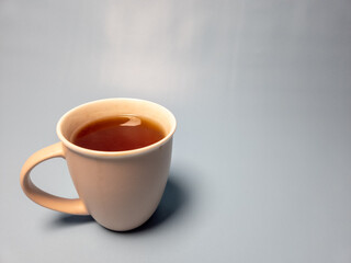 A glass of hot sweet tea isolated on a light blue background