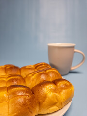 A plate of srikaya torn bread and a glass of sweet tea isolated on a light blue background