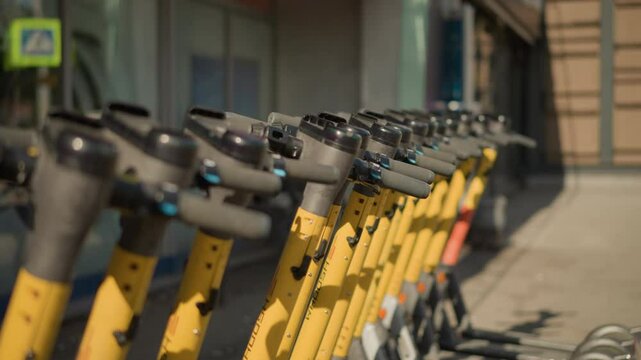 Close-up of yellow electric scooters lined up in urban setting, ready for use, in modern city street, showcasing sustainable transportation options for eco-friendly commuting