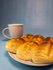 A plate of srikaya torn bread and a glass of sweet tea isolated on a light blue background