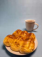 A plate of srikaya torn bread and a glass of sweet tea isolated on a light blue background