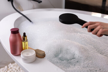 Filling bathtub with bubbles and shower, luxury spa skincare preparation, wellness home relaxation.