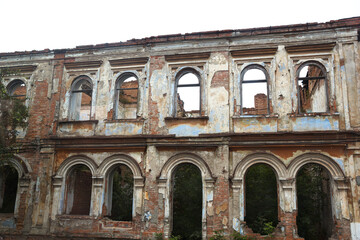 Roofless falling apart abandoned ruined building  with empty windows and plaster going off the walls