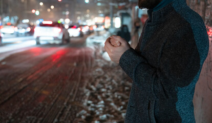 Young Man Shivering at a Bus Stop While Waiting for Public Transport in Cold Weather.