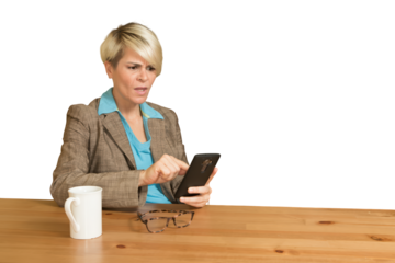 A woman is sitting at a table with a cell phone in her hand